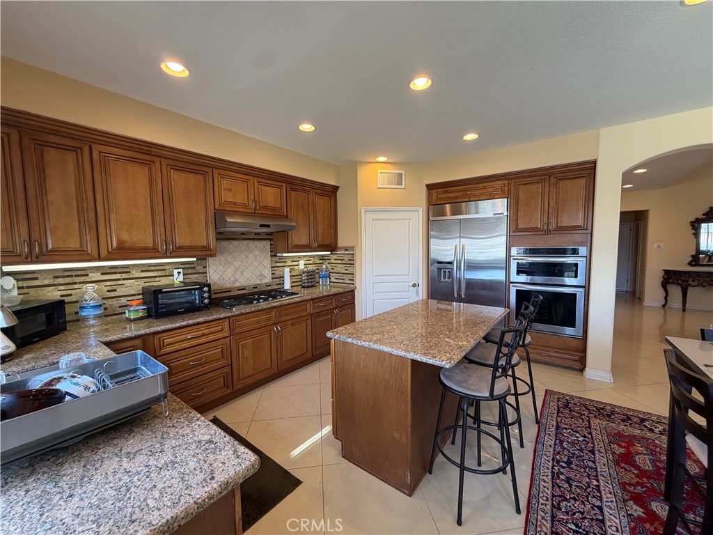 19823 Mariposa Pines Way Porter Ranch, CA 91326 - Photo 11 of 50 a kitchen with stainless steel appliances granite countertop a stove top oven a sink refrigerator and cabinets