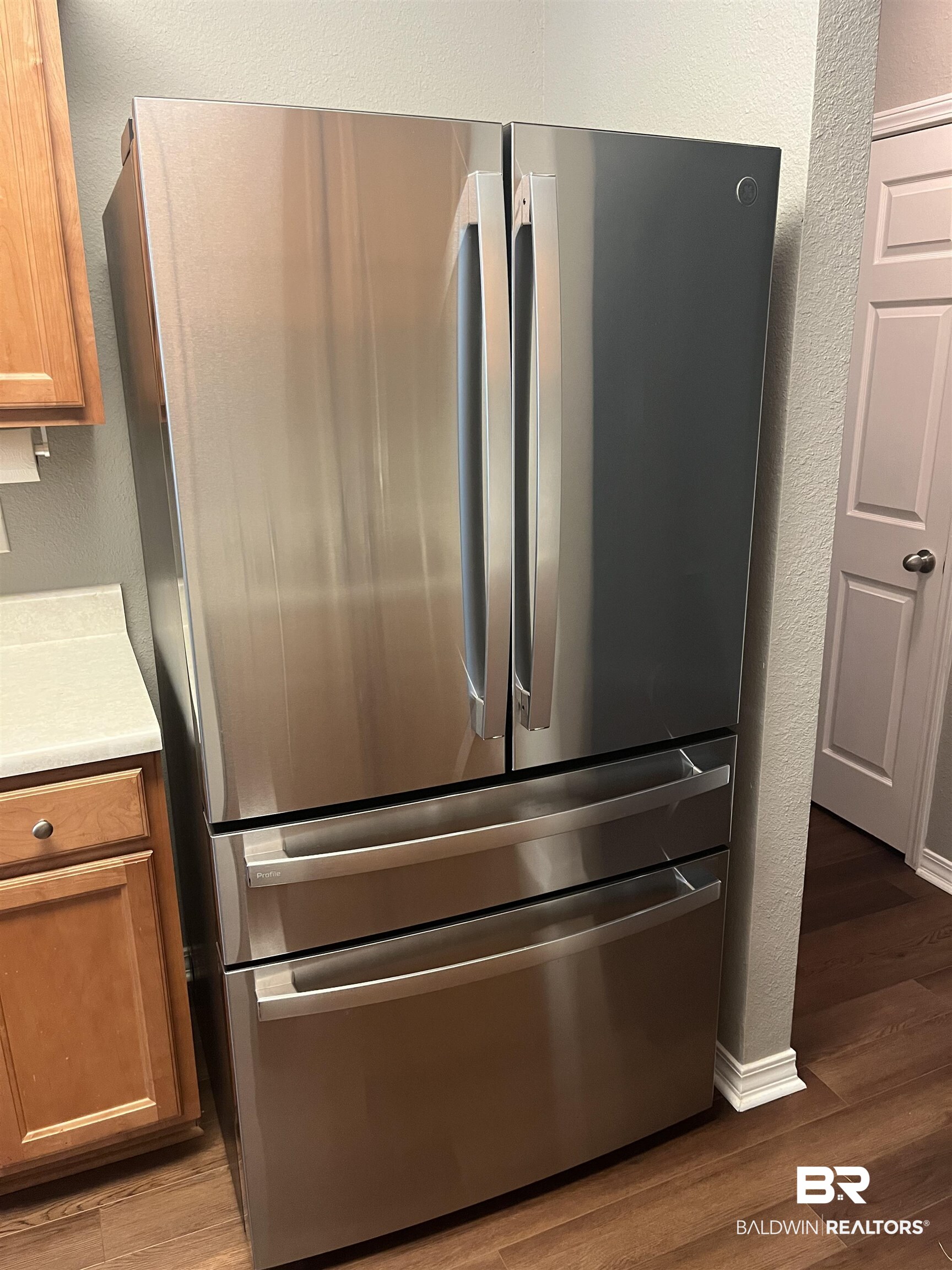309 Cluster Street Foley, AL 36535 - Photo 5 of 38 Stainless steel French door refrigerator with bottom freezer drawers, light wood-finish cabinetry, light countertop, and wood-finish flooring
