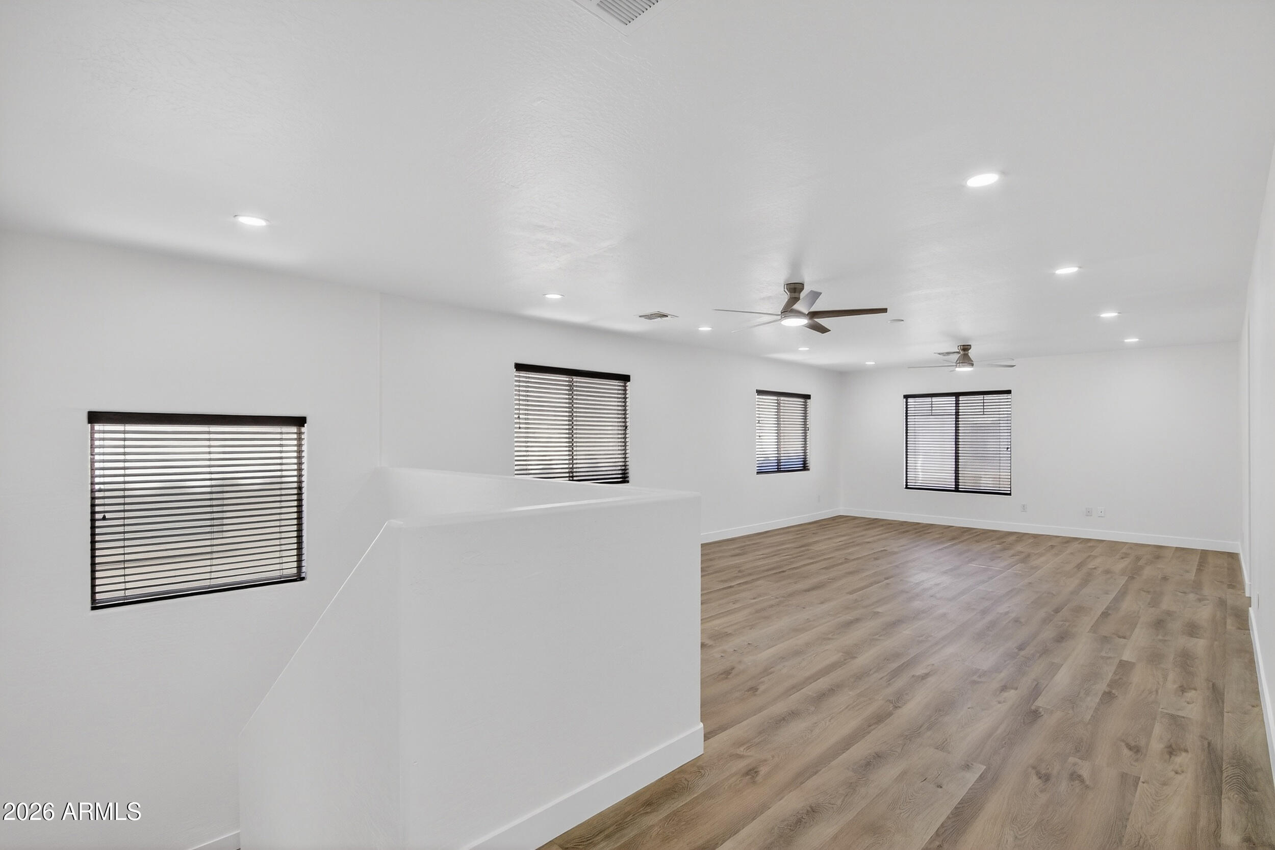 43620 West Cowpath Road Maricopa, AZ 85138 - Photo 24 of 60 an empty room with wooden floor ceiling fan and windows