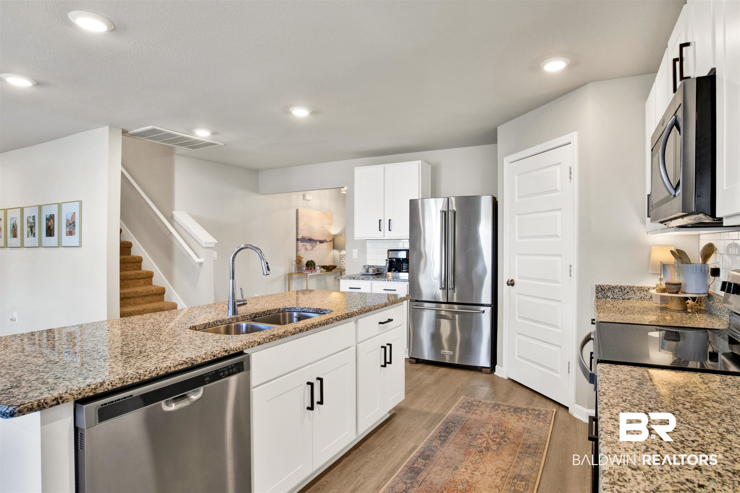 24532 Broken Sound Loop Orange Beach, AL 36561 - Photo 12 of 29 Kitchen with sink, dark hardwood / wood-style flooring, appliances with stainless steel finishes, decorative backsplash, and white cabinetry
