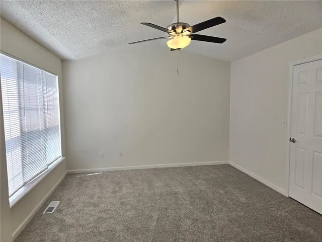 an empty room with a window and a fan