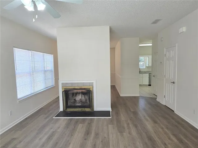 an empty room with wooden floor fireplace and windows