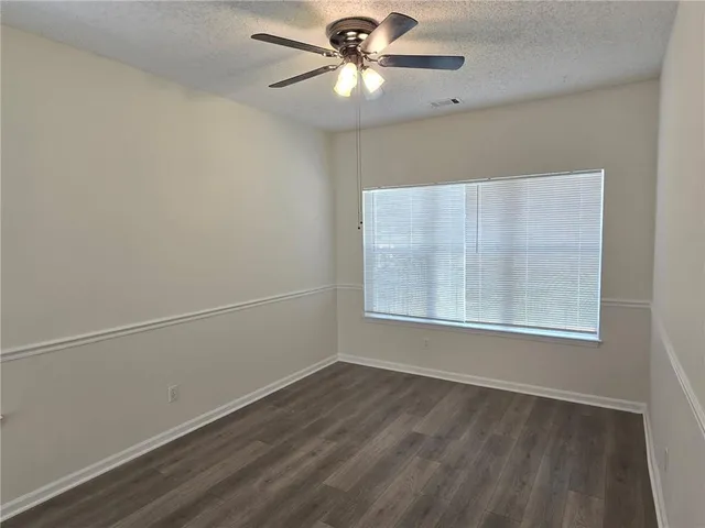 an empty room with a window and a fan