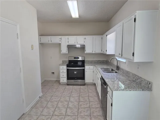 a kitchen with stainless steel appliances granite countertop a stove a sink and a refrigerator