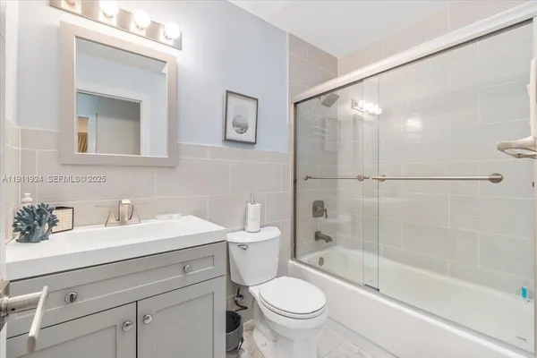 a bathroom with a bathtub shower sink vanity mirror and toilet
