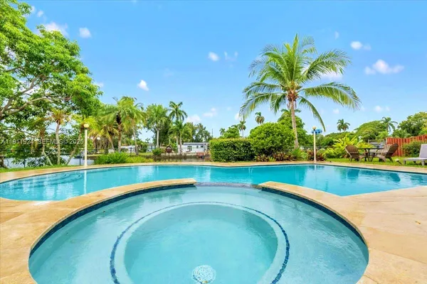 a view of a swimming pool with a yard and palm trees