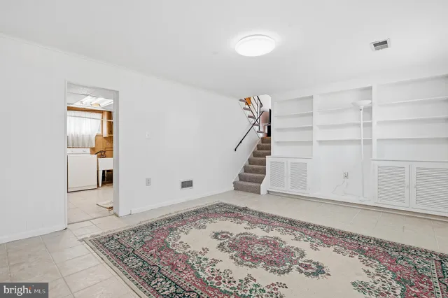 an empty room with a rug and white walls