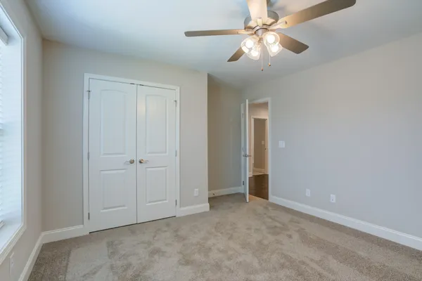 an empty room with closet and a chandelier fan