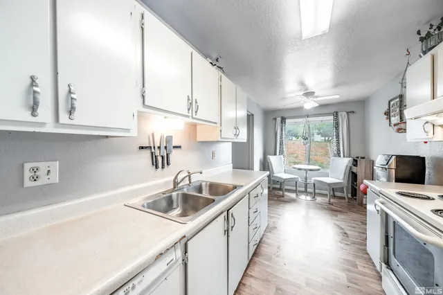 a kitchen with a sink dishwasher a stove and a microwave oven with white cabinets