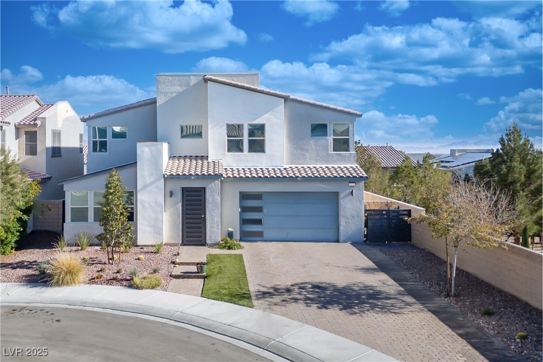 View of front of house with decorative driveway, a garage, stucco siding, and a tile roof