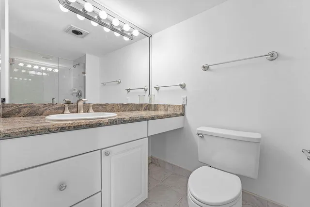 a bathroom with a granite countertop sink a toilet and a mirror