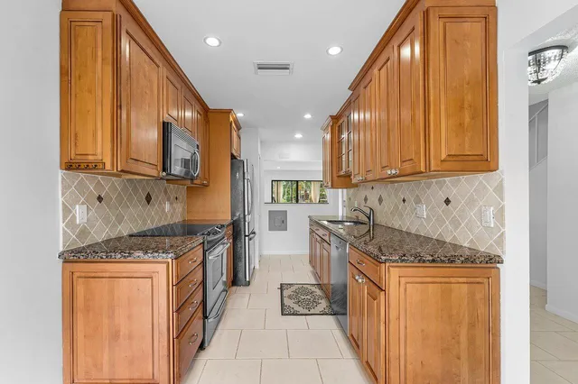 a kitchen with stainless steel appliances granite countertop a stove a sink and a microwave