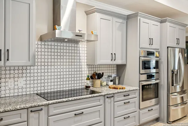 a kitchen with granite countertop white cabinets and stainless steel appliances