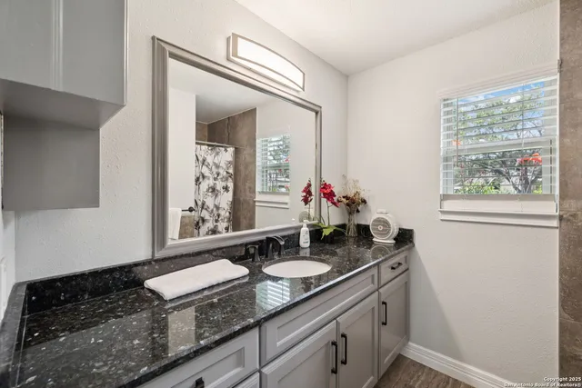 a bathroom with a granite countertop sink a mirror and a window