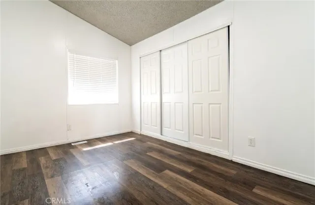 an empty room with wooden floor and windows with curtains