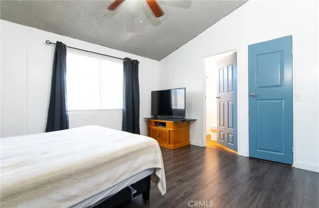 a bedroom with a large bed a flat tv screen and a dresser