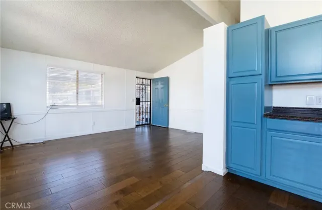 an empty room with wooden floor cabinet and windows