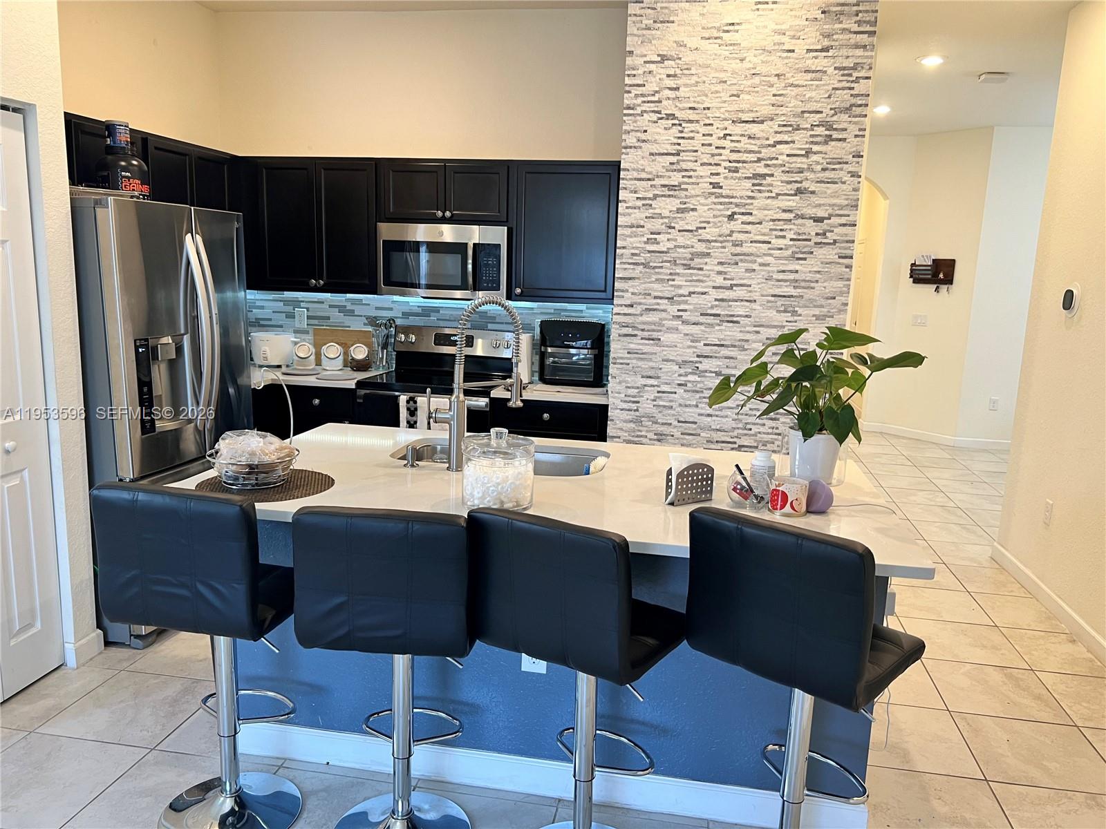 134 Northeast 23rd Terrace Homestead, FL 33033 - Photo 6 of 17 a kitchen with a table chairs refrigerator and microwave