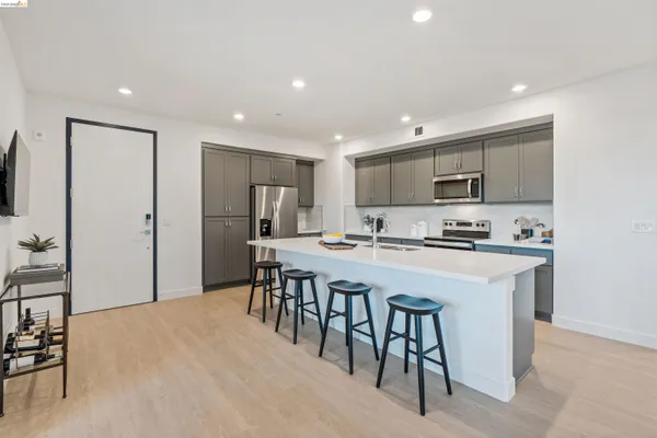 a kitchen with stainless steel appliances kitchen island granite countertop a refrigerator a stove a sink a dining table and chairs with wooden floor