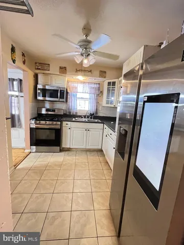 a kitchen with granite countertop a refrigerator a stove top oven and sink