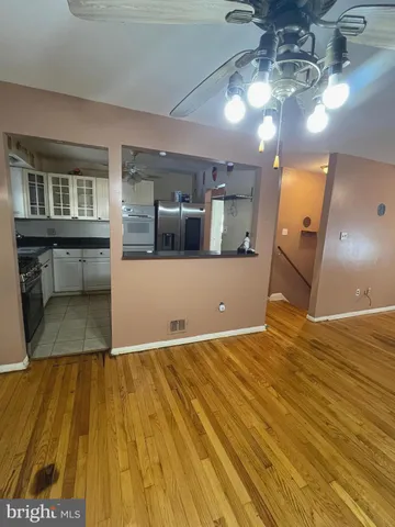 a view of a big room with wooden floor and kitchen view