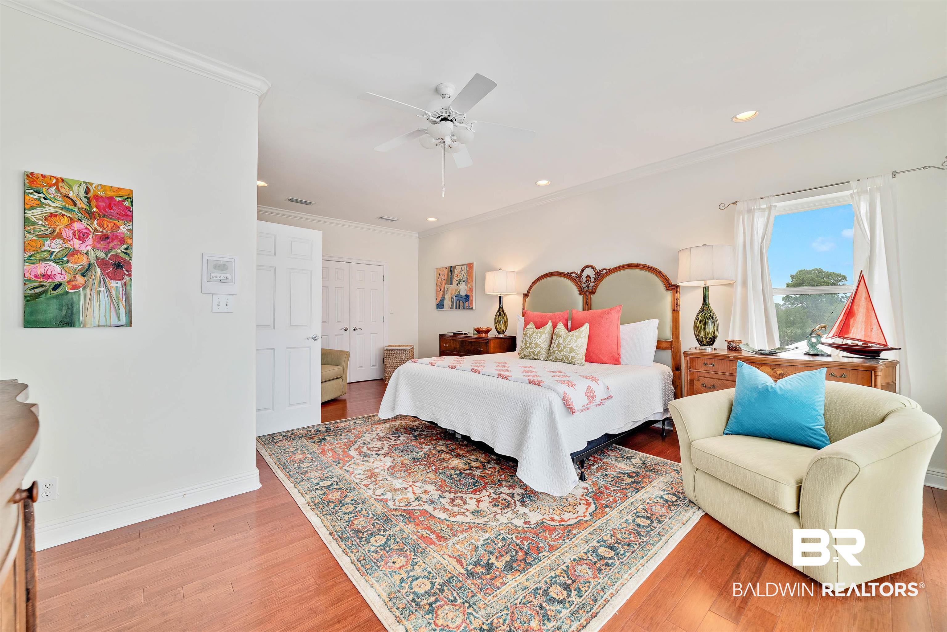 24513 Gulf Bay Road Orange Beach, AL 36561 - Photo 25 of 52 Bedroom featuring crown molding, ceiling fan, hardwood / wood-style flooring, and a closet