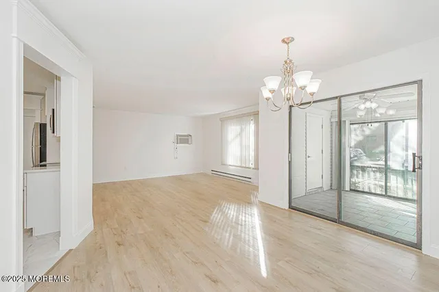 an empty room with wooden floor cabinet and windows