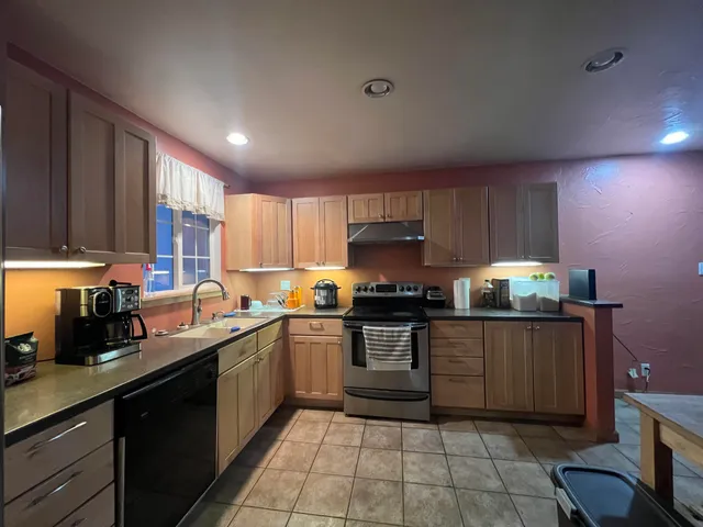 a kitchen with stainless steel appliances granite countertop wooden cabinets a stove top oven a sink and dishwasher