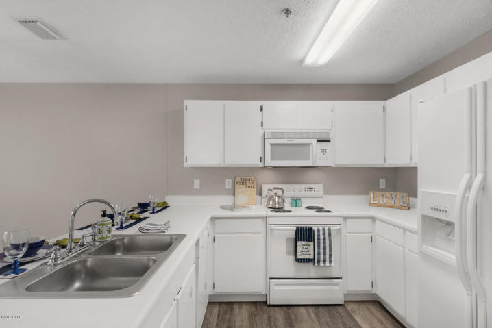 17690 Front Beach Road, Unit D207 Panama City Beach, FL 32413 - Photo 12 of 28 a kitchen with a sink a stove and cabinets