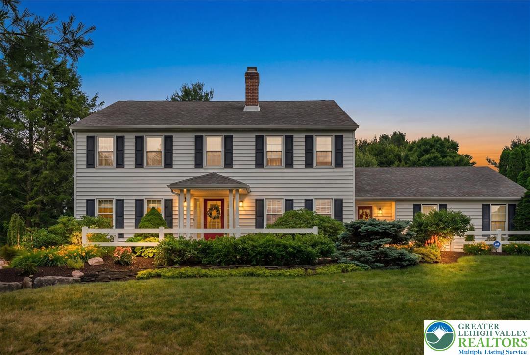 5616 Snowdrift Road Orefield, PA 18069 - Photo 2 of 36 A classic colonial home features a welcoming covered entry and verdant, well-maintained landscaping under a twilight sky.