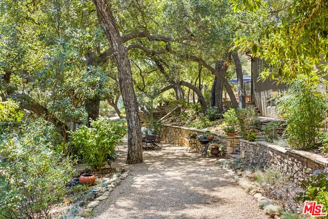 a view of backyard with table and chairs and large trees