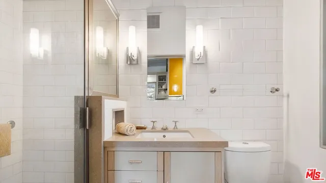 a bathroom with a granite countertop sink toilet and mirror
