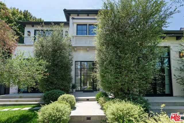 a front view of a house with plants and trees