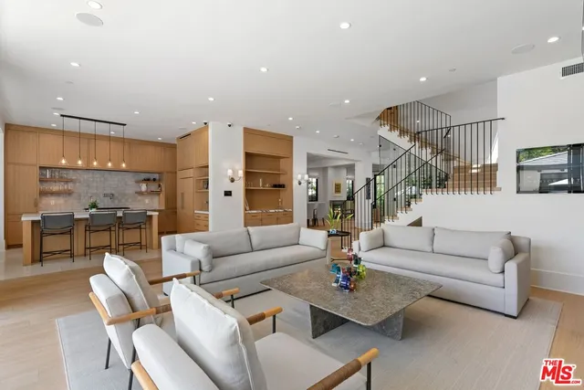 a living room with furniture kitchen view and a large window