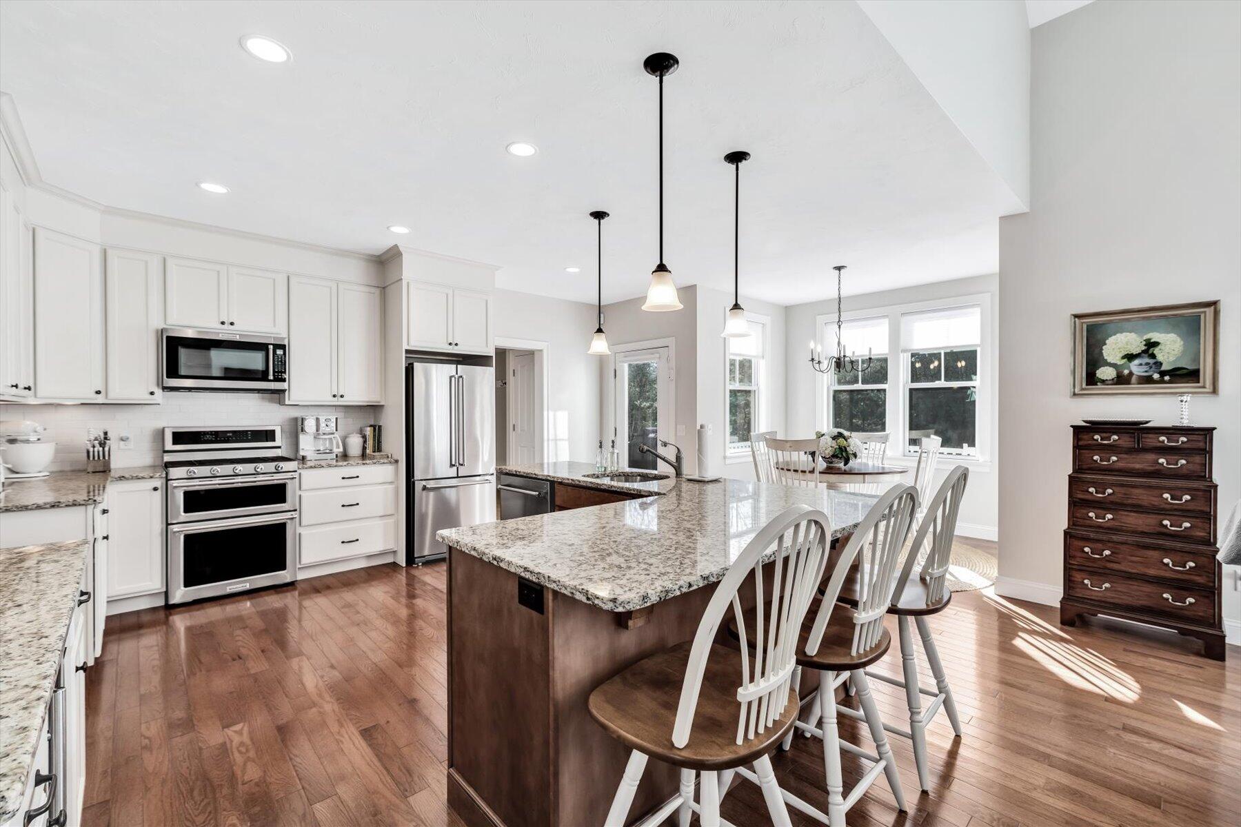 66 Eagle Drive Mashpee, MA 02649 - Photo 11 of 36 a open kitchen with stainless steel appliances granite countertop a stove a refrigerator a kitchen island a dining table and chairs with wooden floor