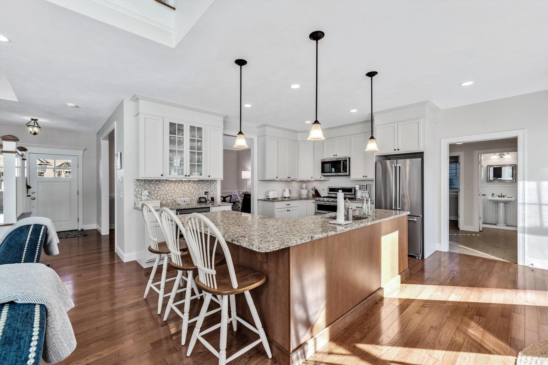 66 Eagle Drive Mashpee, MA 02649 - Photo 7 of 36 a large kitchen with stainless steel appliances kitchen island granite countertop a table chairs and a wooden floor