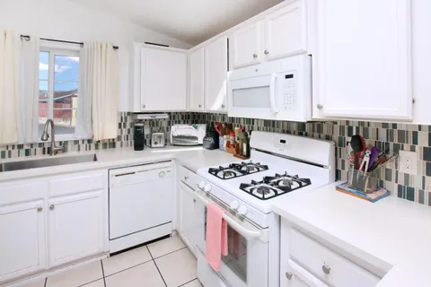 a kitchen with white cabinets and appliances