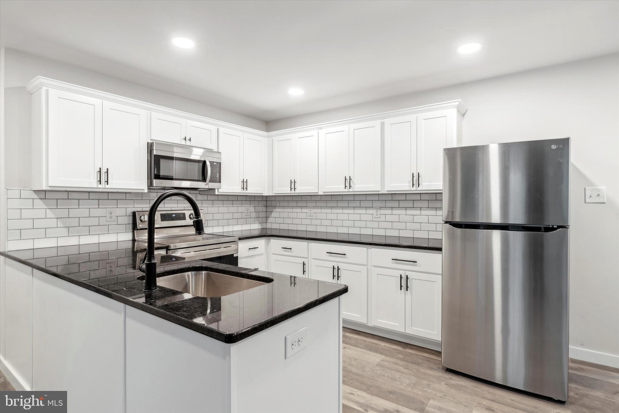 a kitchen with kitchen island a sink white cabinets and stainless steel appliances