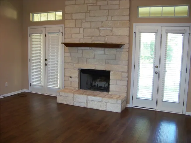 an empty room with wooden floor a fireplace and windows