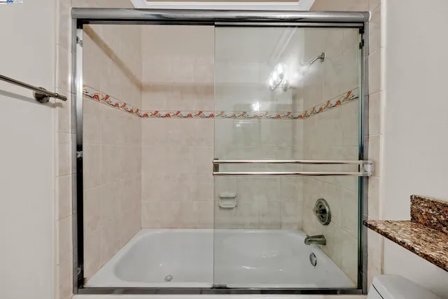 a bathroom with a granite countertop sink mirror toilet and bathtub