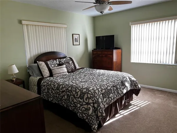 a bedroom with a bed and a flat tv screen on the dresser