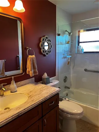a bathroom with a granite countertop toilet sink and mirror