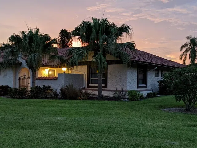 a front view of a house with a garden and trees