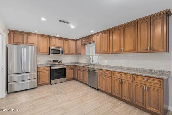 a kitchen with stainless steel appliances granite countertop a refrigerator sink and cabinets