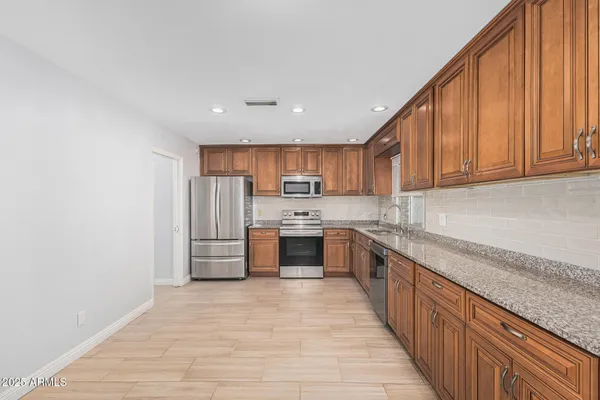 a large kitchen with cabinets wooden floor and stainless steel appliances