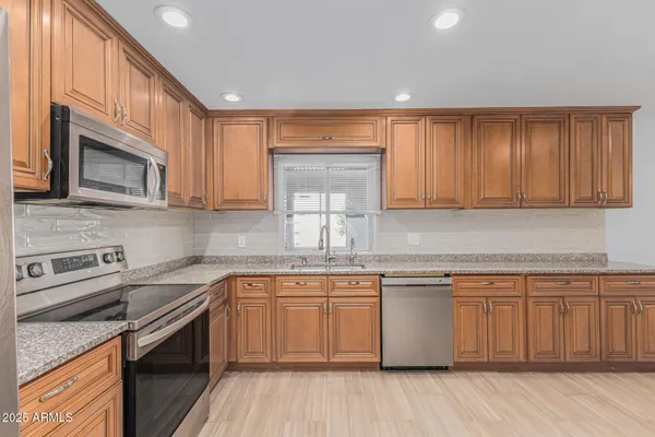 a kitchen with a sink cabinets stainless steel appliances and a window