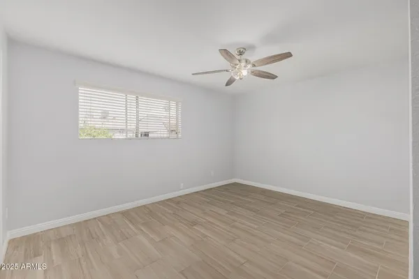 a view of empty room with wooden floor and fan