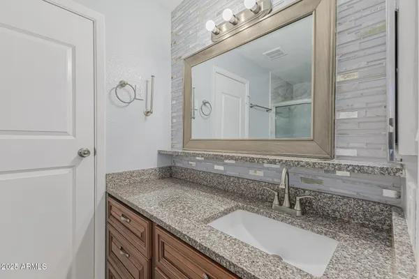a bathroom with a granite countertop sink and a mirror