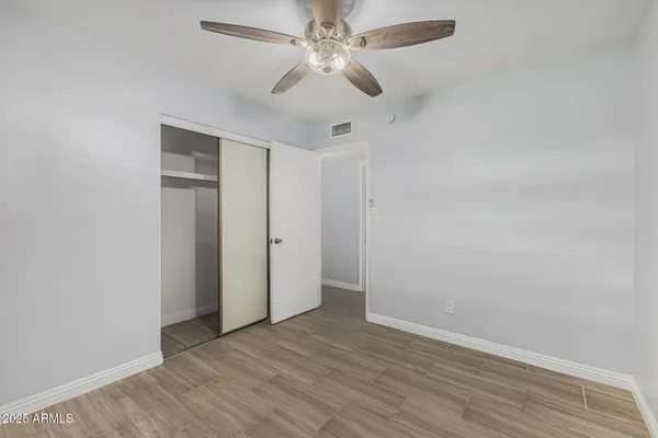 an empty room with wooden floor ceiling fan and window