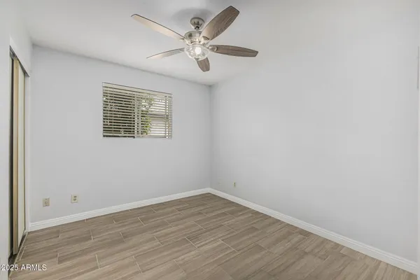 an empty room with wooden floor and ceiling fan